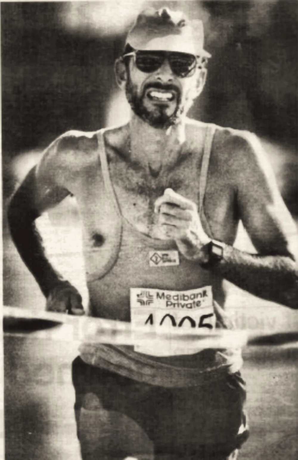 A marathon runner breaking the finish tape, wearing a Medibank Private race number.