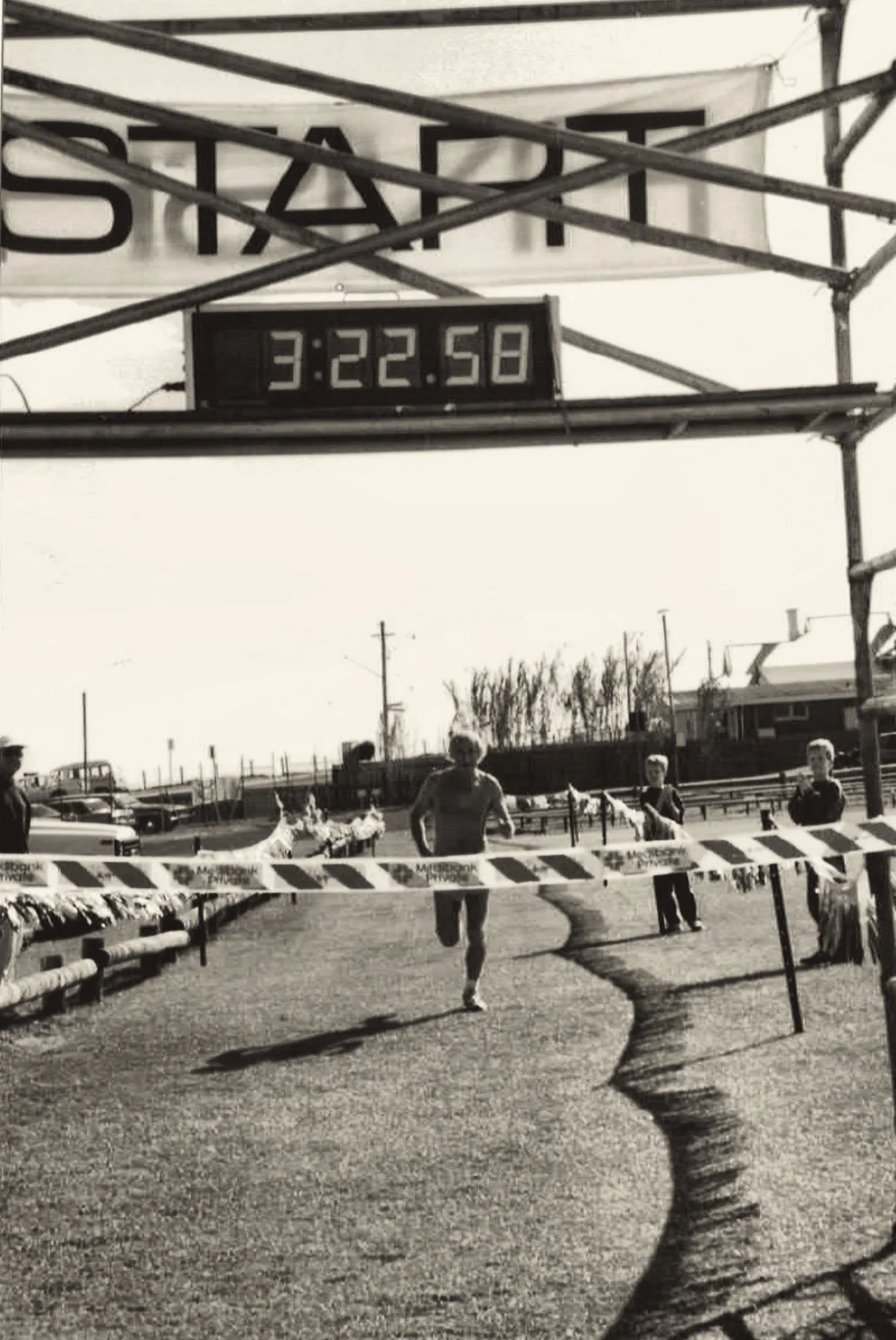 A runner approaching the finish beneath the START gantry with the race clock showing 3:22:58.