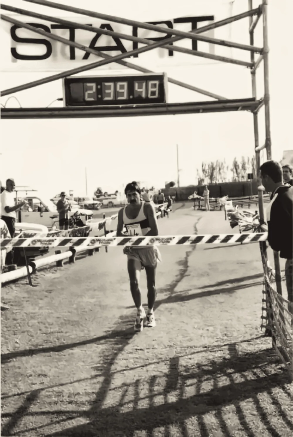 A runner breaking the finish tape under the START gantry, race clock reading 2:39:48.