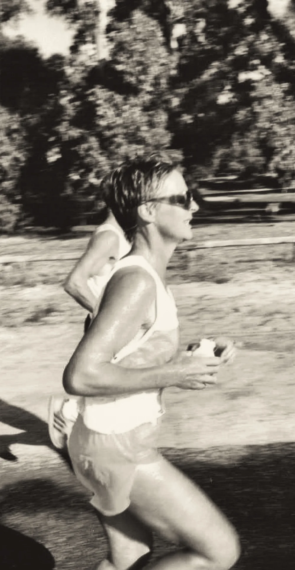 A woman running on the course in sunglasses, mid-stride.