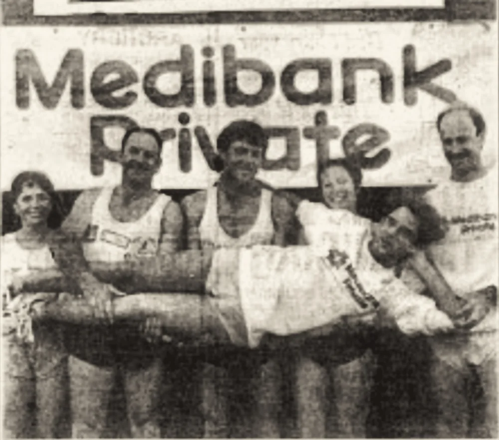 Runners standing together beneath a Medibank Private banner at the finish.